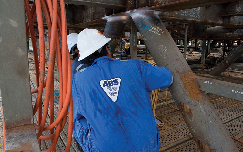 Workers in overalls inspecting steel structure.credit_abs